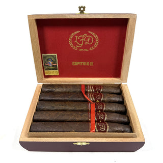 Open cigar box with cigars and a red interior, featuring a logo and text.