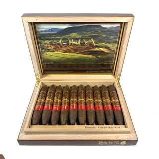 Open cigar box displaying cigars with a scenic lid design on a white background
